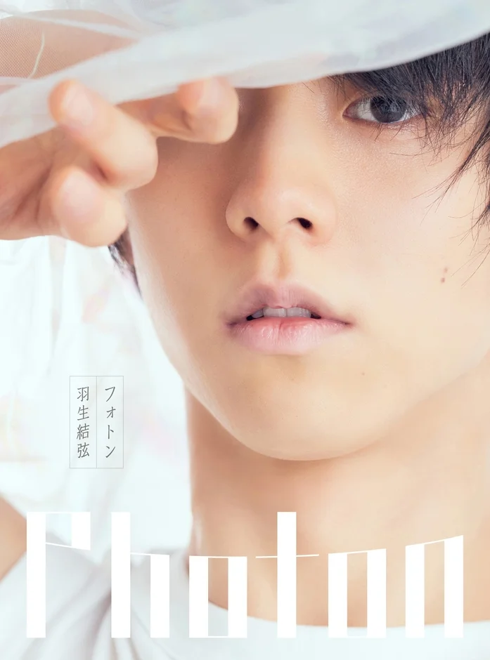 フィギュアスケート選手の羽生結弦さんの顔のクローズアップポートレート。白い薄布で顔の一部が覆われ、透明感のある表情が印象的です。画像下部には「photon」の文字が見えます。